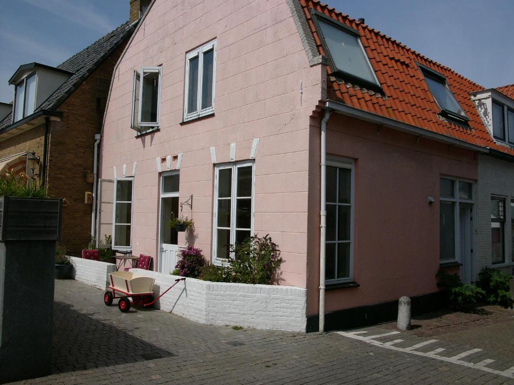 a pink house with a wheelbarrow in front of it at Dar Cho Apartment in Zandvoort