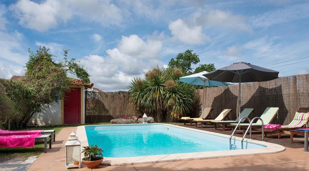 a swimming pool with chairs and an umbrella at Casa Ci in Vila Franca