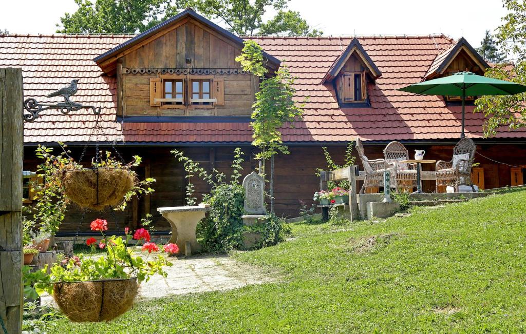 a house with a garden with chairs and an umbrella at Kuca Suncani brijeg in Pokupsko