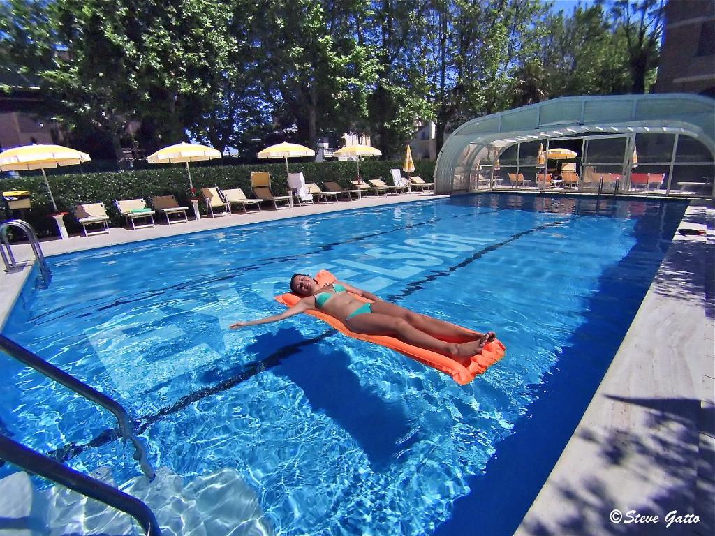 uma mulher está deitada numa piscina em Hotel Excelsior em Cervia