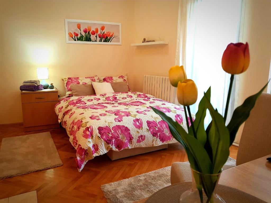 ein Schlafzimmer mit einem Bett und einer Vase aus Blumen in der Unterkunft Apartman Lenka in Banja Koviljača