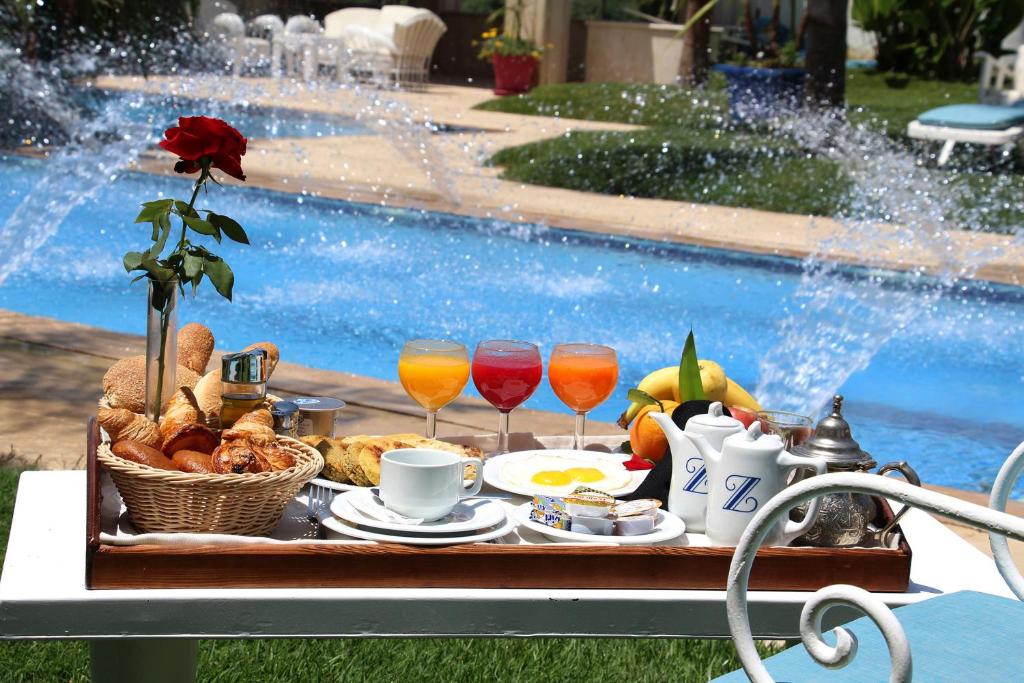 uma bandeja de comida e bebidas numa mesa ao lado de uma piscina em Zaki Suites Hotel & Spa em Meknès