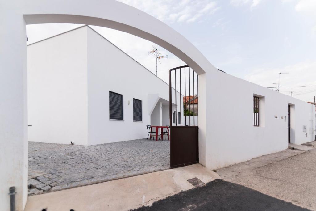 une arche menant à un bâtiment blanc avec une cour dans l'établissement Villa UA, à Pias