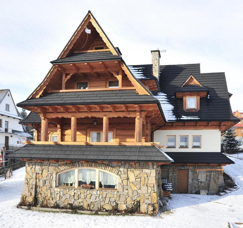 een groot houten huis met een groot dak bij Jodłowy Dworek in Bukowina Tatrzańska