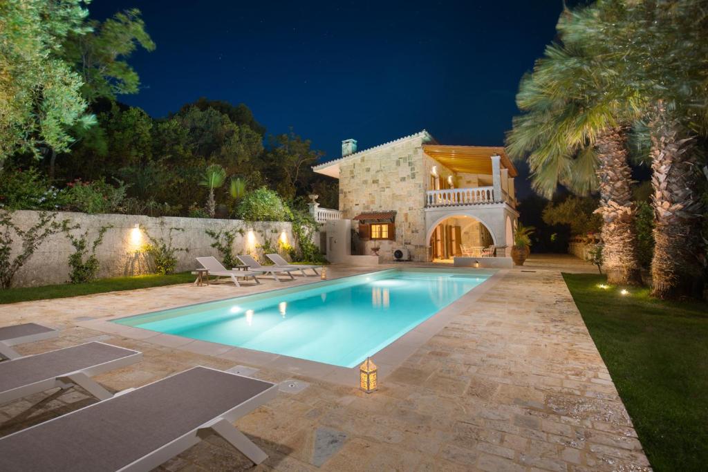 a swimming pool in front of a house at night at Ionian Garden Villas - Villa Pietra in Benitses