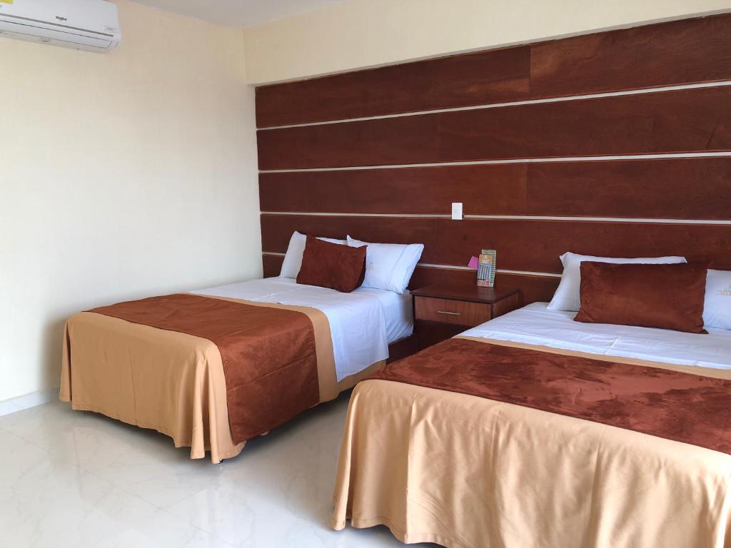 2 bedden in een hotelkamer bij Hotel Mirto in Puebla