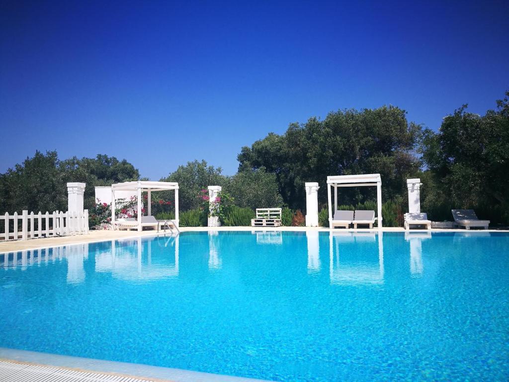 una grande piscina con sedie e gazebo di Agriturismo Masseria San Leonardo a Savelletri