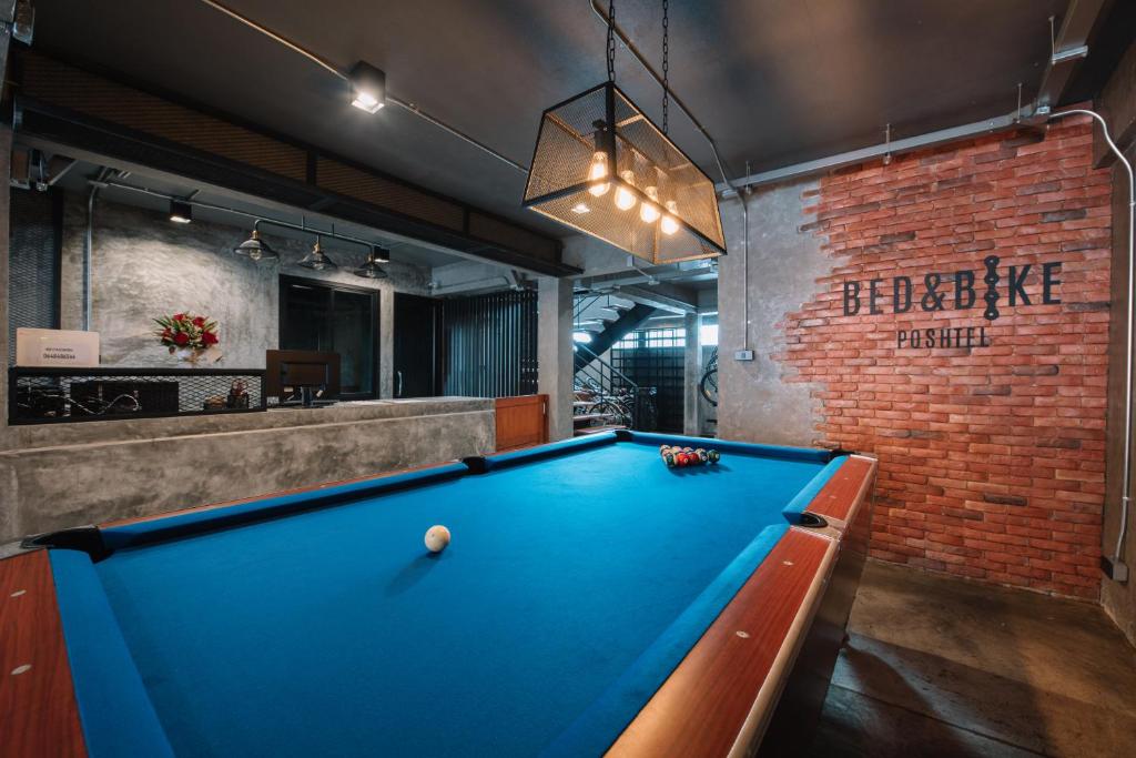 a pool table in a room with a brick wall at Bed & Bike Hostel in Chiang Rai