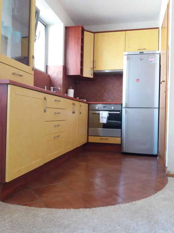 cocina con armarios de madera y nevera de acero inoxidable en Apartament, en Hajnówka