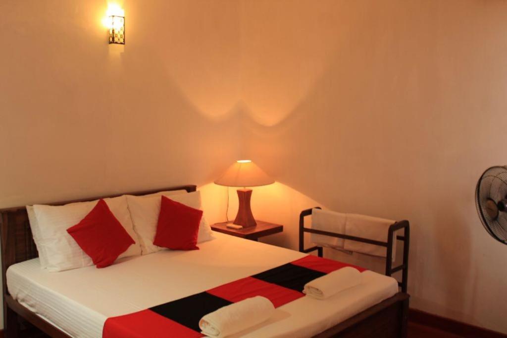 a bedroom with a bed with red pillows and a lamp at 47 Alfred House - Free Pickup from Kandy City in Kandy