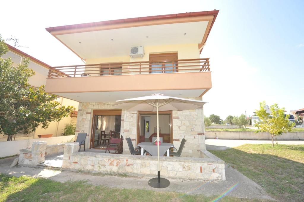 een villa met een balkon en een tafel met een parasol bij Marina Maisonette by RentalsPro Kallithea Halkidiki in Kallithea