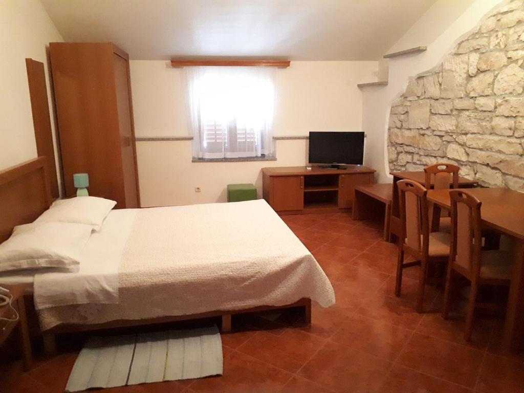 Schlafzimmer mit einem Bett, einem Tisch und einem TV in der Unterkunft Apartments Lav Poreč in Poreč