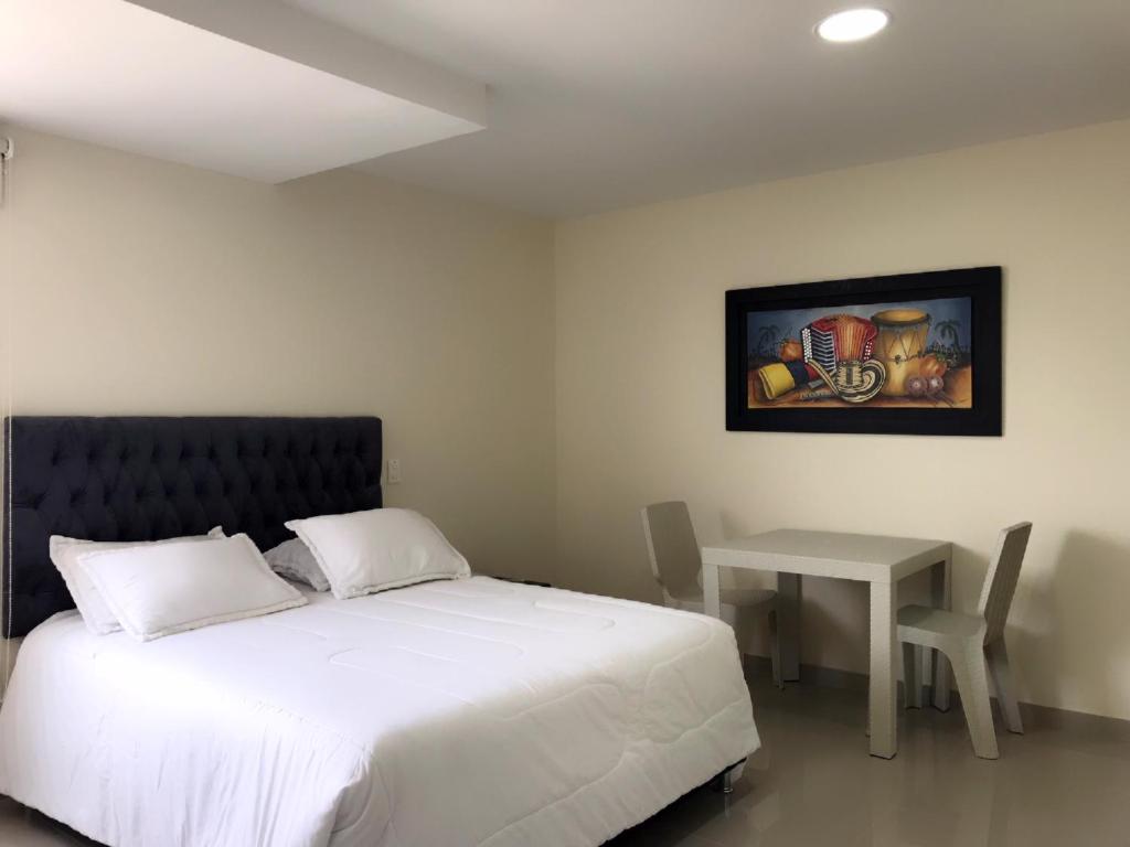 a bedroom with a bed and a table and a painting at Hotel Continental Express in Barranquilla