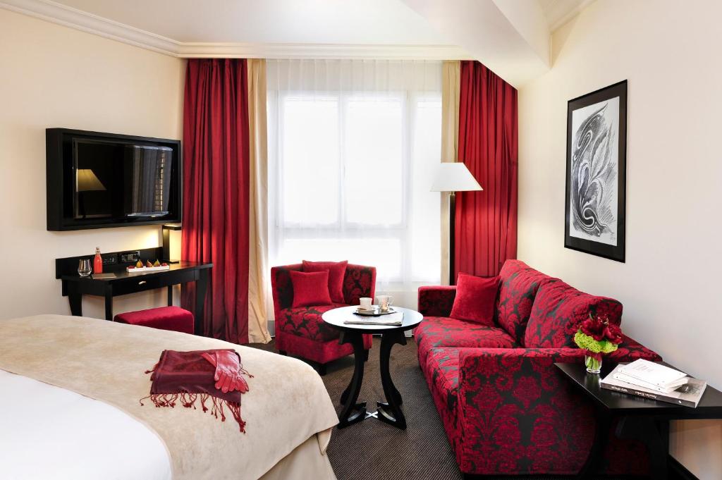 a hotel room with a bed and a red couch at Hôtel Tiffany by Fassbind in Geneva
