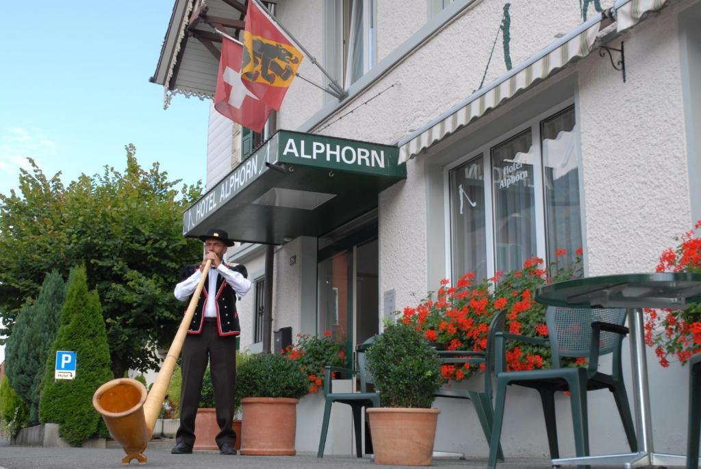 um homem segurando um taco de beisebol em frente a uma loja em Hotel Alphorn em Interlaken