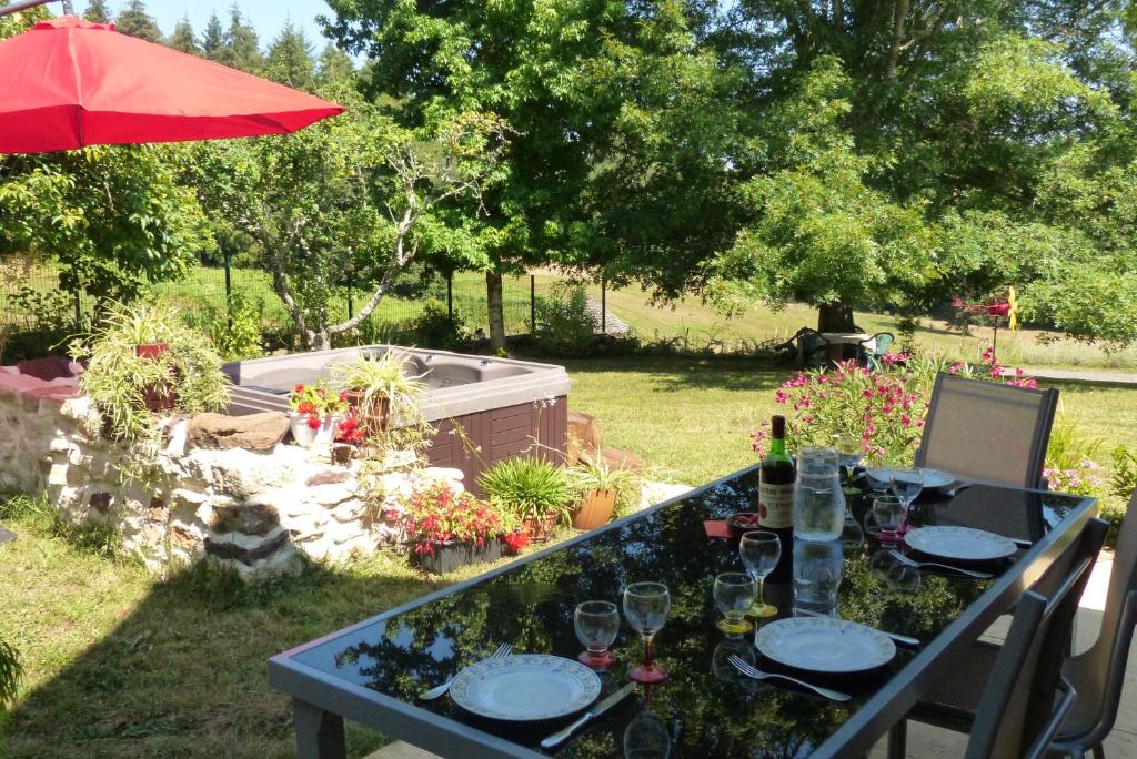 Frayssinet-le-GélatにあるGîte l'Orée du bois - maison individuelle avec jacuzzi privéの庭園のテーブル(ワイングラス付)