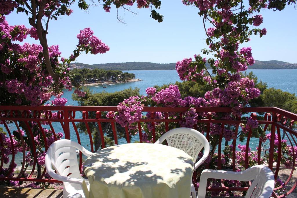 una mesa y sillas sentadas en un balcón con flores en Apartments Ana Trogir, en Trogir