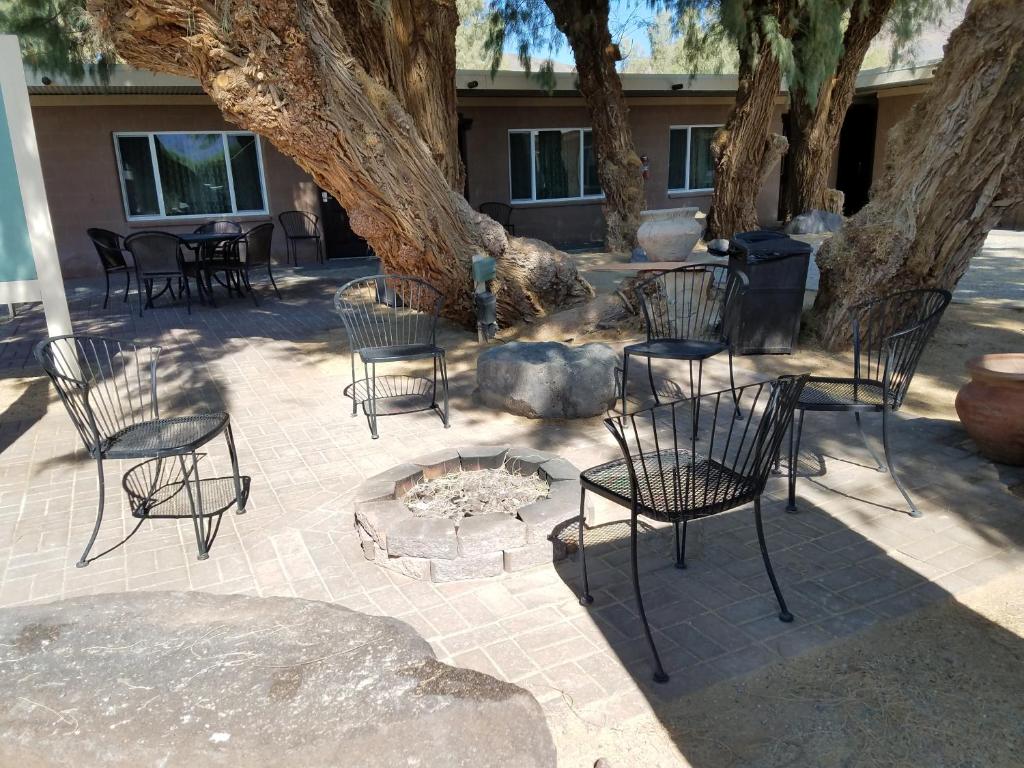 eine Gruppe von Stühlen und eine Feuerstelle unter einem Baum in der Unterkunft Shoshone Inn in Shoshone