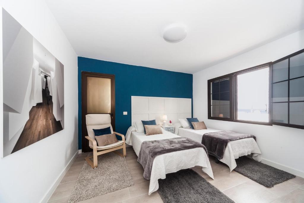 1 dormitorio con 2 camas y pared azul en Luxury Beach Apartments en Playa Honda