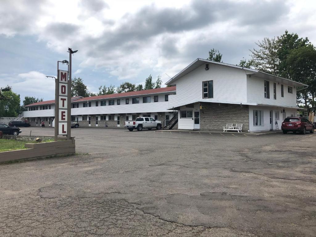 un edificio blanco con un cartel de motel en un estacionamiento en Voyageur Motel en Thunder Bay