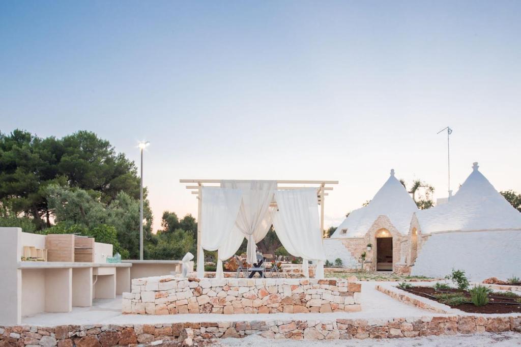 a pavilion with white curtains and a church at Trulli arabesco in Ceglie Messapica