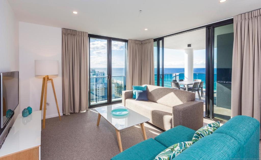 a living room filled with furniture and a large window at Boardwalk Burleigh Beach - Official in Gold Coast