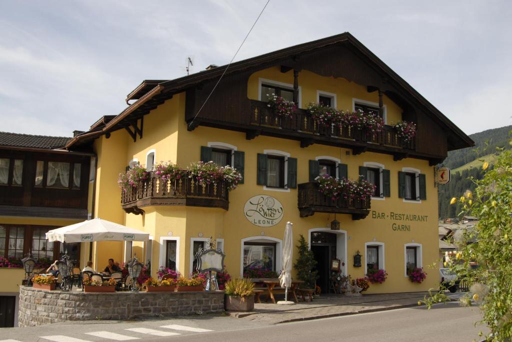 ein gelbes Gebäude mit Blumenkästen und Balkonen darauf in der Unterkunft Hotel Loewenwirt in Sexten