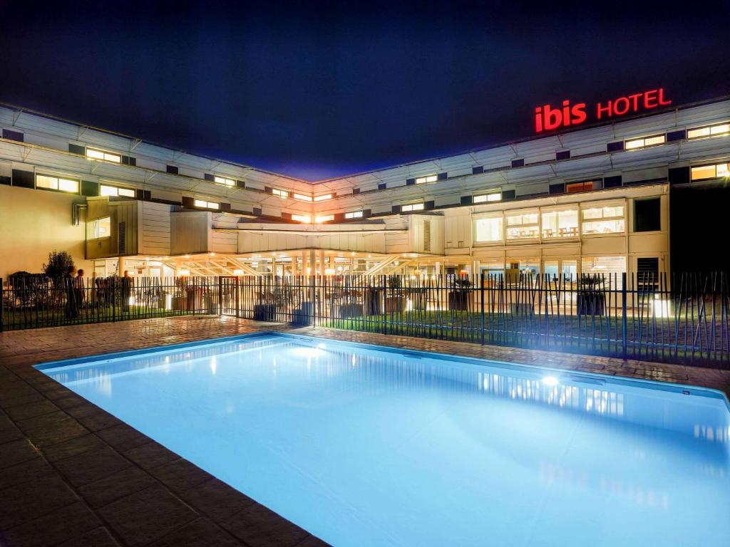 une piscine devant un immeuble la nuit dans l'établissement ibis Site du Futuroscope, à Chasseneuil-du-Poitou