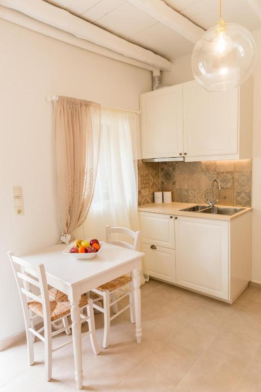 biała kuchnia z białym stołem i krzesłami w obiekcie Romantic house Priotissa II w mieście Tympáki
