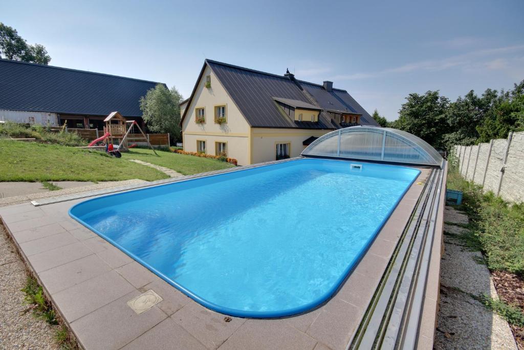 duży niebieski basen z domem w tle w obiekcie Guest House Pod Hájkem w mieście Horní Branná