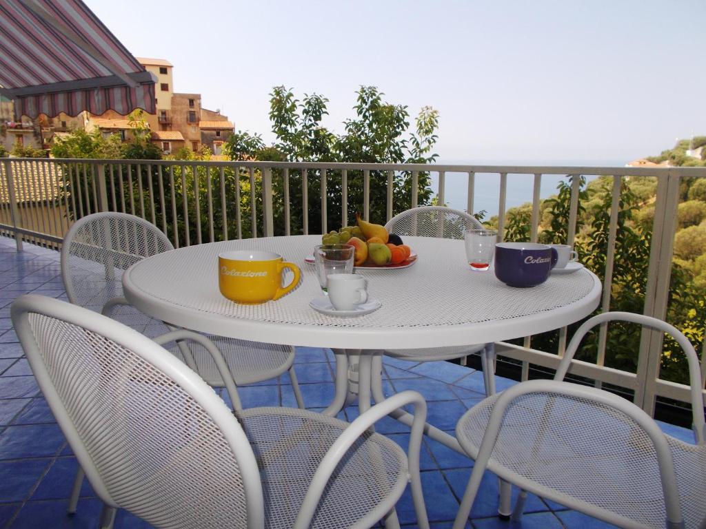 a white table with a plate of fruit on a balcony at Donna Ester - Discover Cilento in Pisciotta