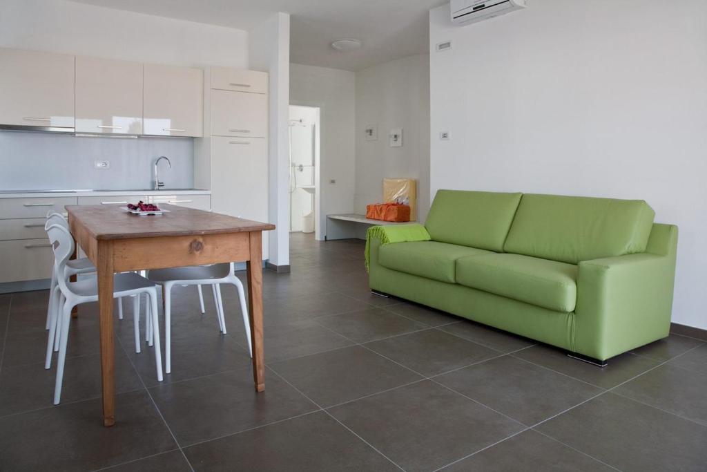 a living room with a green couch and a table at Casa Rosa dei Venti in Nago-Torbole