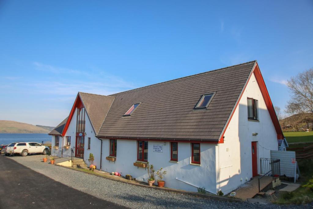 una casa blanca con techo negro en Arle Lodge, en Tobermory