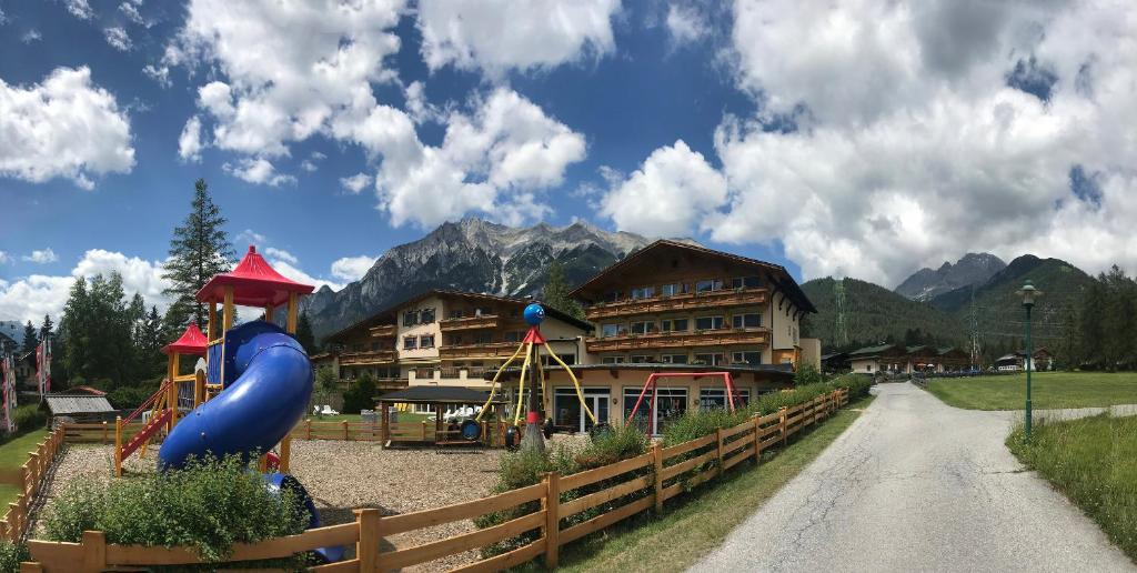 a playground in front of a building with mountains at Kinderhotel Lärchenhof in Obsteig