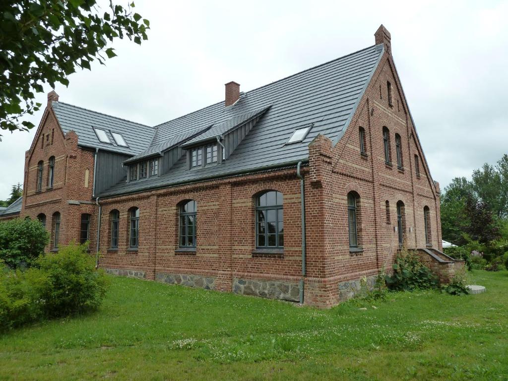un grand bâtiment en briques avec un toit noir dans l'établissement Gutshaus Altbauhof, à Dargun