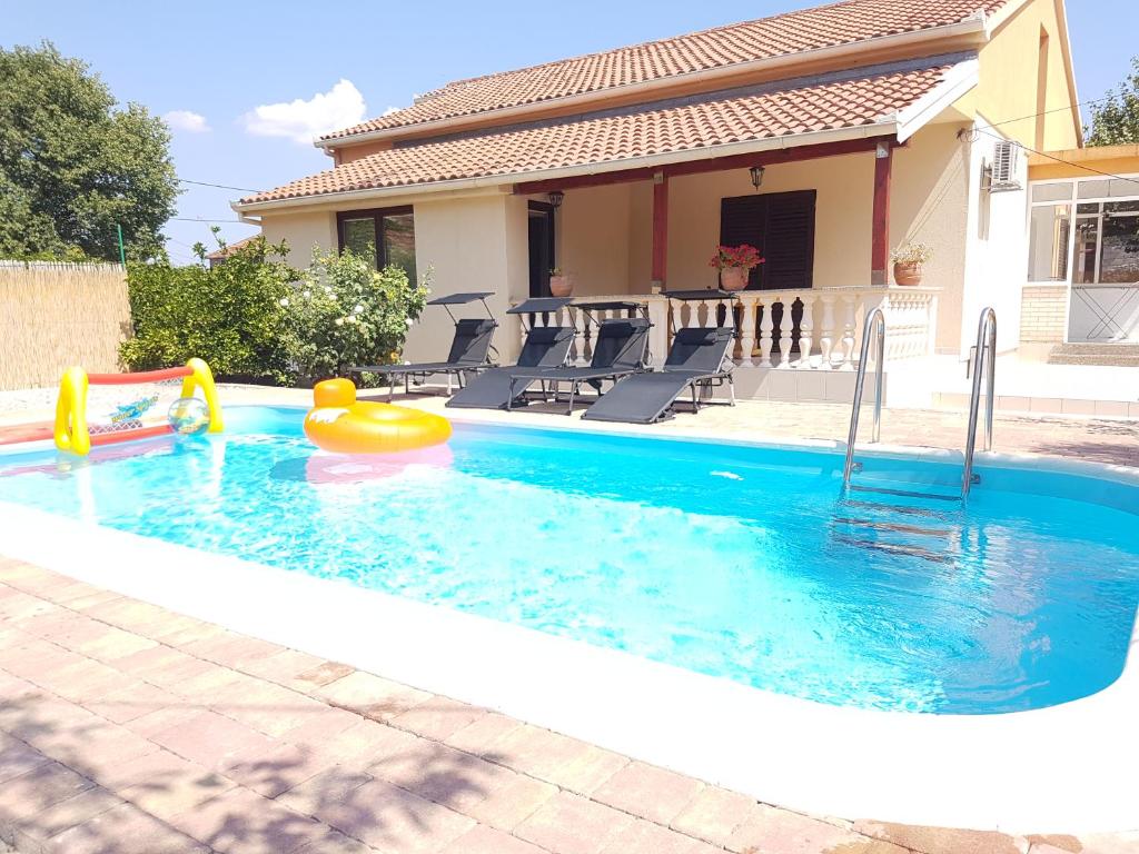 a swimming pool with a pool noodle in front of a house at Vacation home Duilo in Donji Zemunik