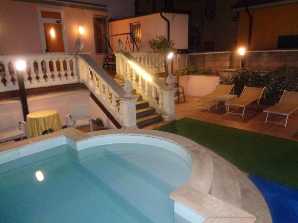 a swimming pool with a staircase and chairs in a building at Hotel Innocenti in Montecatini Terme