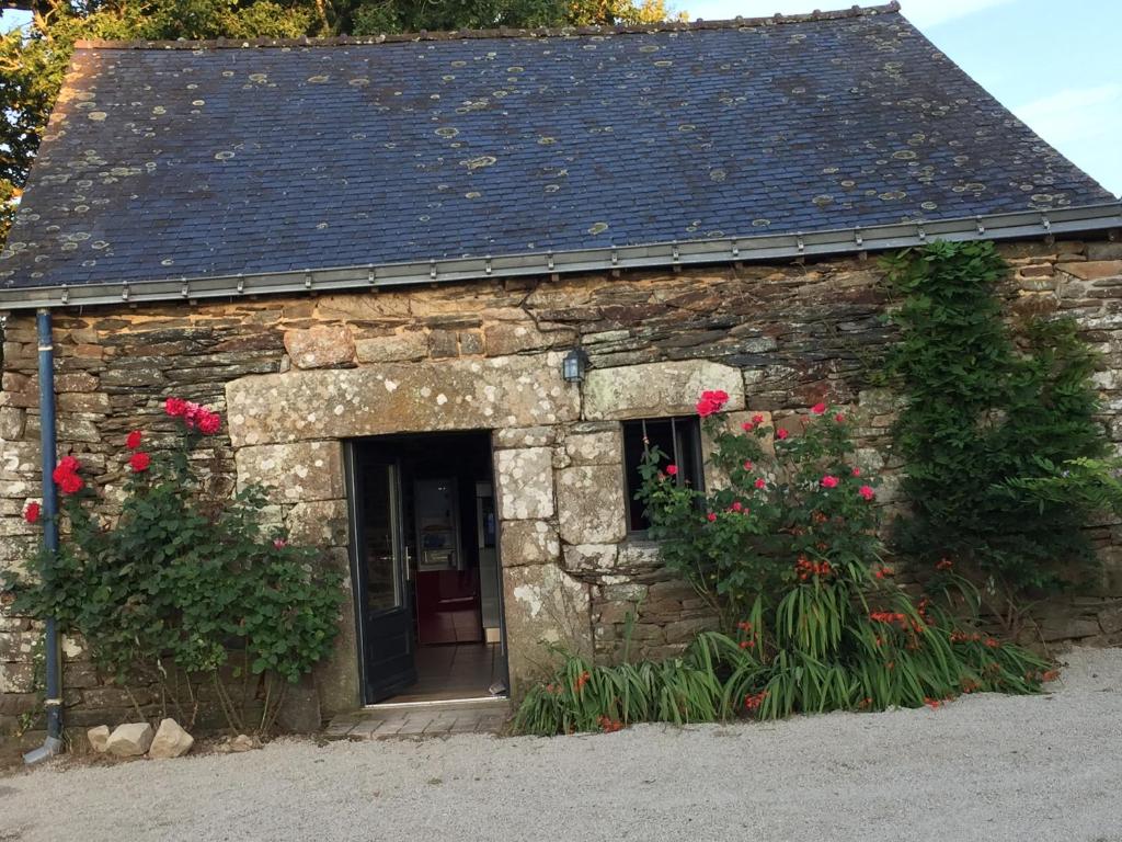 um edifício de pedra com flores vermelhas em frente em Callac gîte P 8 em Plumelec