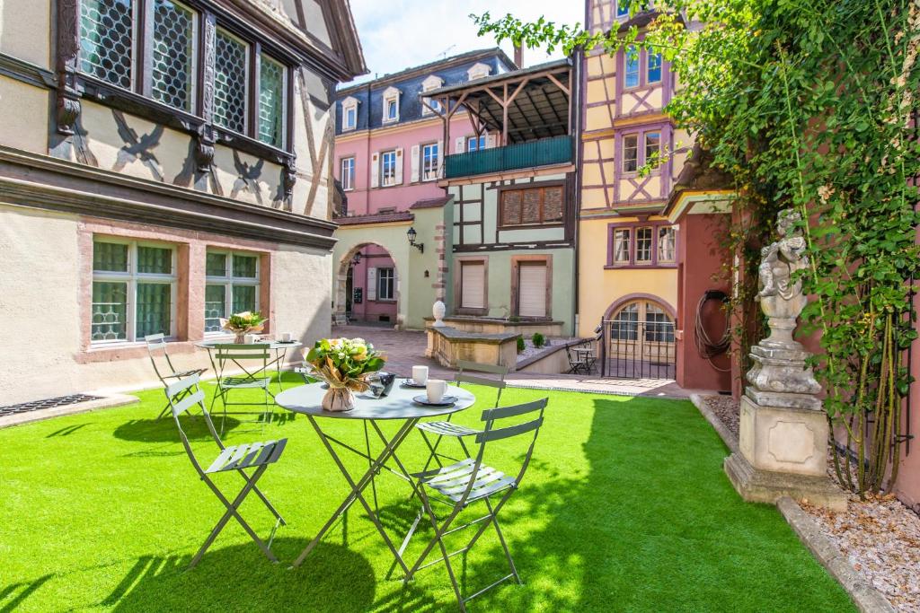 コルマールにあるLe 1615 - Luxe et Spaの緑の芝生の上にテーブルと椅子が備わる中庭