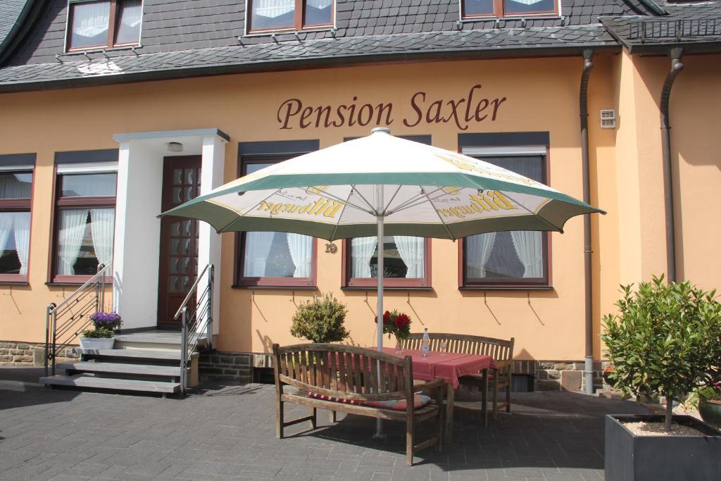 einem Tisch mit einem Regenschirm vor einem Gebäude in der Unterkunft Pension-Saxler in Neichen