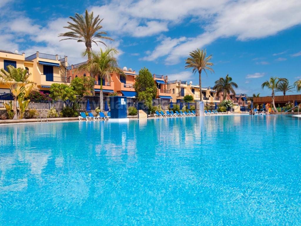 uma grande piscina num resort com palmeiras em Villa Feliz 128 em Meloneras