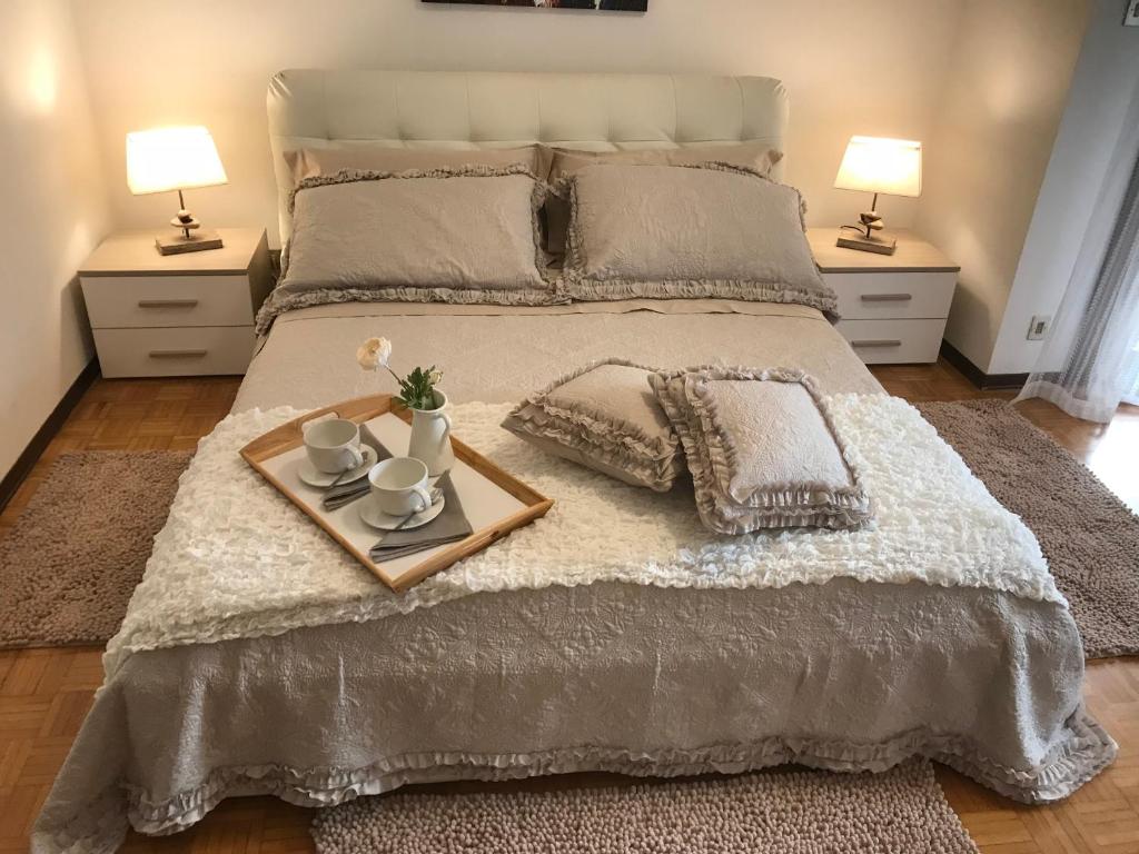 een bed met een dienblad met twee kopjes en twee lampen bij Casa Martini Abano in Abano Terme