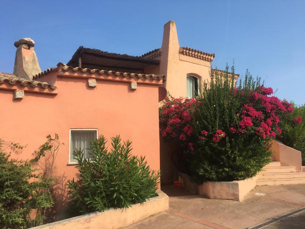 ein Haus mit rosa Blumen auf der Seite in der Unterkunft Appartamenti Costa Rossa Cala Rossa in Isola Rossa