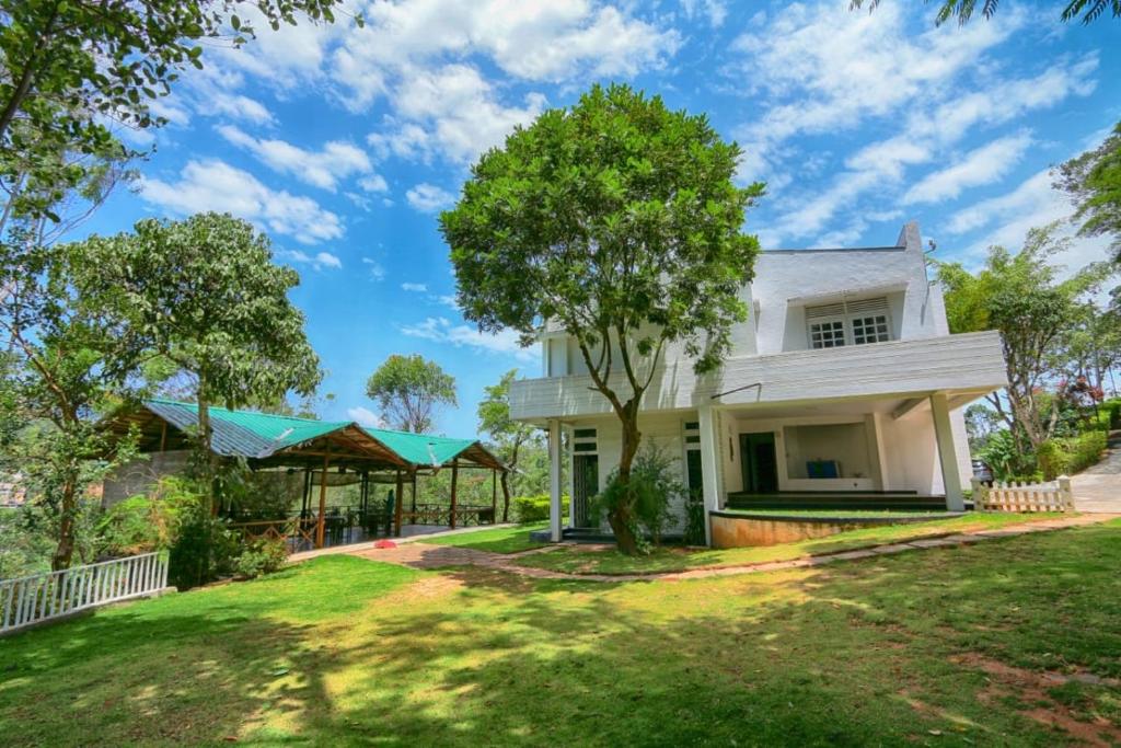 une maison blanche avec un arbre dans la cour dans l'établissement Homies Place - Bistro, à Bandarawela