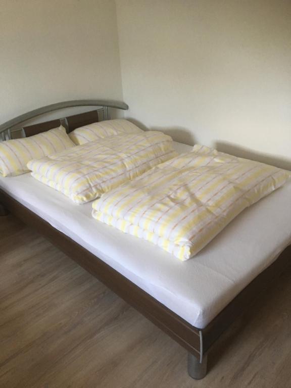 Cama con sábanas y almohadas amarillas y blancas en Haus Ursula en Brake