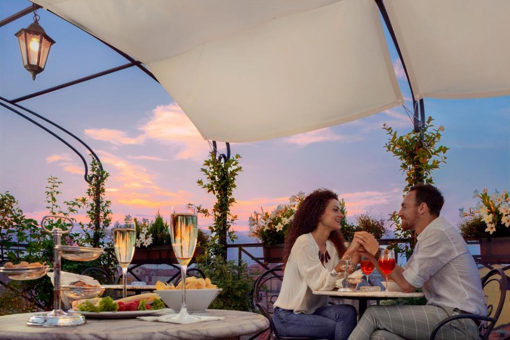 a man and woman sitting at a table with wine glasses at Hotel Firenze in Venice