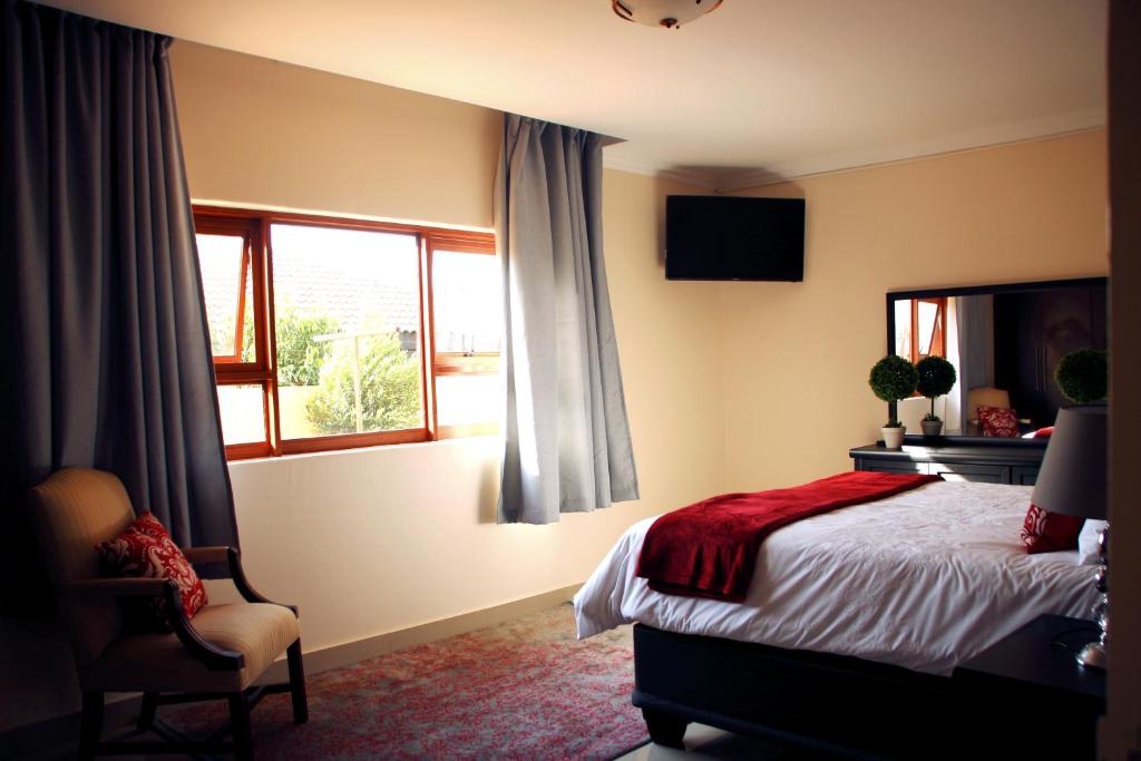 a bedroom with a bed and a window and a chair at Green Haven Luxury Apartments in Ezulwini