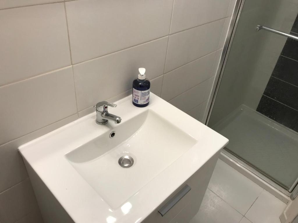 a white bathroom sink with a bottle of soap on it at Lumineux T2 Vieille ville 3 pers parking gratuit - by La Source d&#39;OrFée in Boulogne-sur-Mer