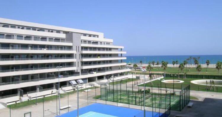 ein großes Gebäude mit einem Tennisplatz davor in der Unterkunft Apartamento Lujo, Primera linea playa, Garaje, Wifi, Piscina climatizada in Roquetas de Mar