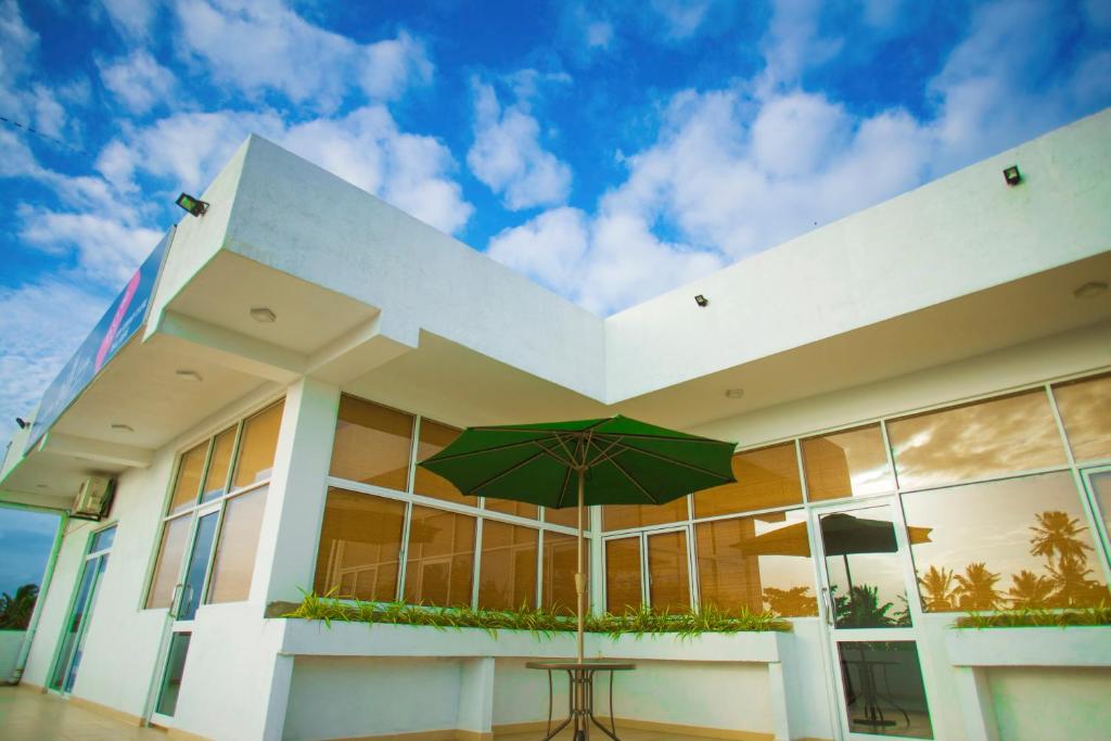 a building with a green umbrella in front of it at Bliss Apartment Hikkaduwa in Hikkaduwa